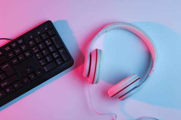 Gaming equipmen. Keyboard and headphone with neon gradient pink-blue light. Music concept. Computer game competition. Top view - Φωτογραφία, εικόνα