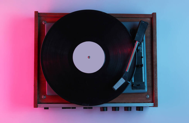 Retro style music concept. Vinyl record player with gradient pink-blue neon light. Pop culture. 80s. - Photo, Image
