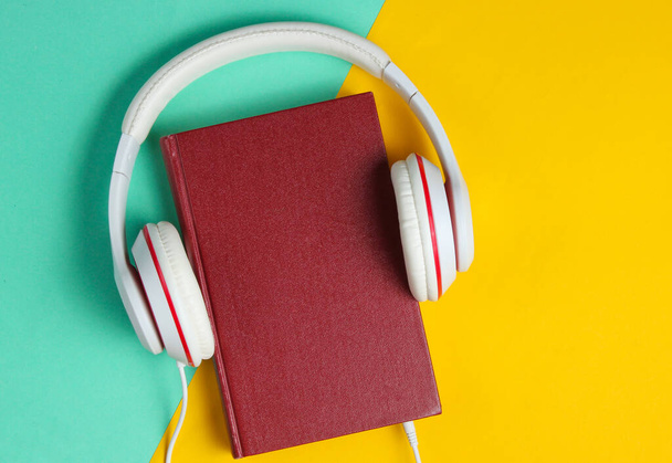 Minimalismo en línea escuchar libros concepto. Audiolibro Libro con auriculares sobre fondo de color. Vista superior - Foto, imagen