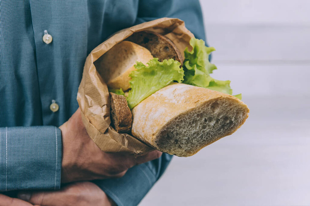 Bread and products in a paper bag in the hands of a guy. on a white background - 写真・画像