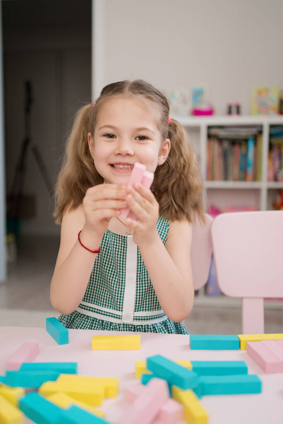 Beautiful caucasian girl playing with wooden multi-colored blocks - Photo, Image