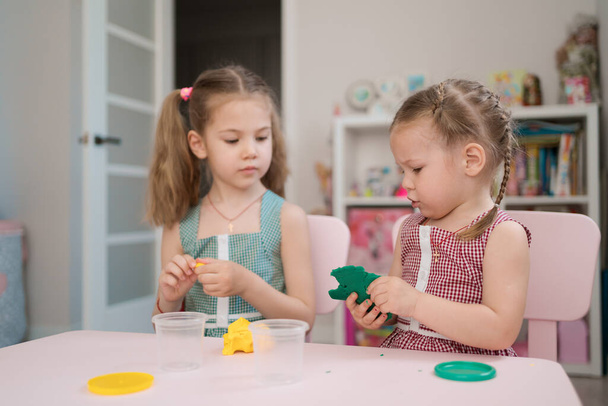 Cute little girls moulding from plasticine on pink table - Photo, Image