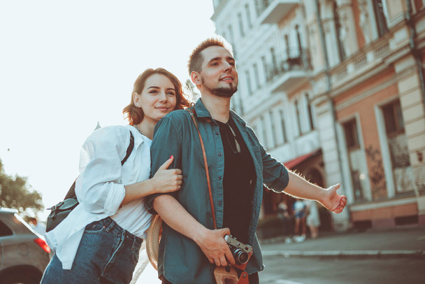 Young happy stylish couple of lovers catch a car in the city. Hitchhiking concept - Foto, imagen