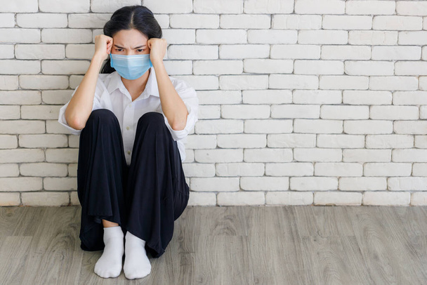 Young Asian woman wearing masks is worried as she is quarantined to the house during the outbreak of the COVID 19 virus. stay at home. - Fotografie, Obrázek