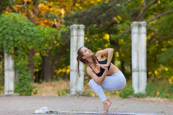 Yoga e fitness. Jovem praticando equilíbrio ioga pose ao ar livre. Exercício de ginástica no parque. - Foto, Imagem