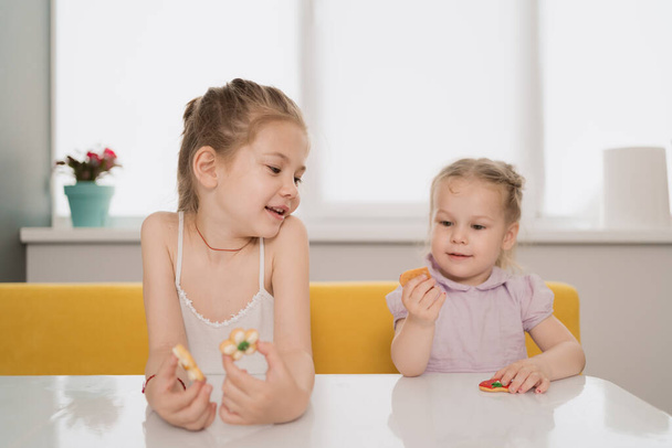 Meninas comendo biscoitos na mesa em casa - Foto, Imagem