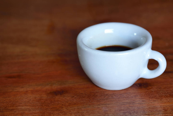 Una taza vieja blanca para los soportes del espresso con el café en una tabla de madera
 - Foto, Imagen