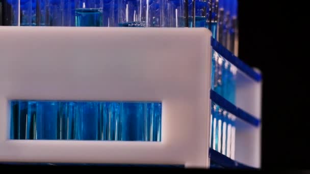 4K laboratuvarında siyah bir arkaplan üzerinde dönen mavi sıvılı test tüpleri - Video, Çekim
