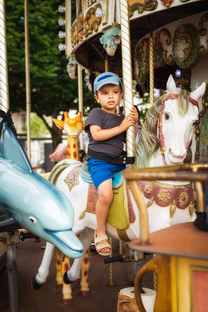 Niño pequeño en el caballo carrusel
 - Foto, imagen