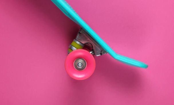 ピンクの背景にプラスチック製のミニクルーザーボード。パステルカラーのトレンド。夏の楽しみ。若者のミニマリズムの概念。トップ表示 - 写真・画像