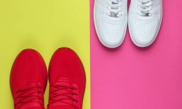 Two pairs of sneakers on a neon color background. White and red shoes. Top view - Photo, Image