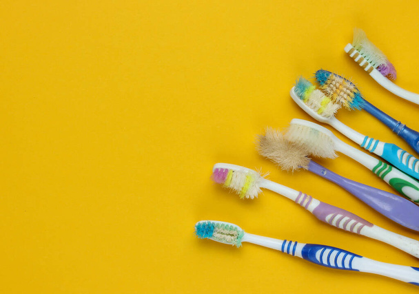 Oude gebruikte tandenborstels op gele achtergrond. Tandheelkundige zorg concept. Bovenaanzicht. Kopieerruimte - Foto, afbeelding