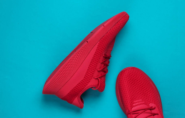 Stylish red sports shoes for running on blue background. Top view - Φωτογραφία, εικόνα