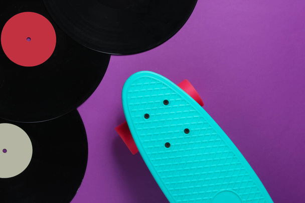 紫色の背景に巡洋艦ボードとビニールレコード。若者のレトロなスタイルのコンセプト。80年代。トップ表示 - 写真・画像