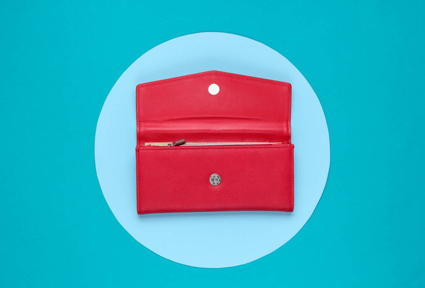 Stílusos női piros bőr pénztárca a háttérben kék pasztell körrel. Kreatív minimalista divat csendélet. Felülnézet - Fotó, kép