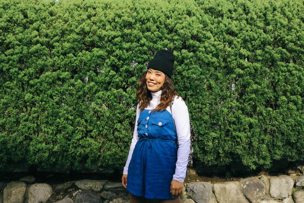 Ασιάτισσα γυναίκα hipster θέτει με πράσινο φόντο δέντρο στον κήπο - Φωτογραφία, εικόνα