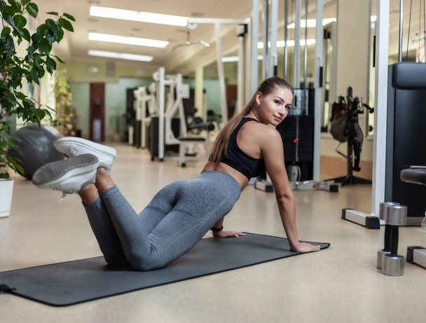 Slim fit woman in sportswear getting ready doing push-ups from the floor in the gym. Healthy lifestyle concept - Foto, afbeelding
