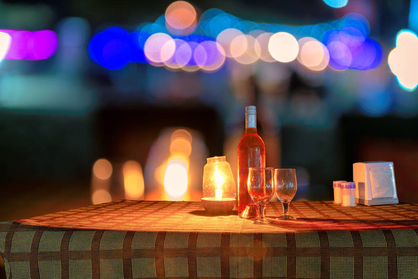 Strandfeest 's nachts in strandcafé met fles rozenwijn en glazen op tafel, GOA, India.. - Foto, afbeelding