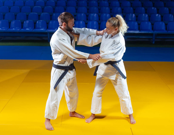 Bojová umění. Spořitelny. Sportovní muž a žena v bílém kimonu vlak judo zachytí ve sportovní hale - Fotografie, Obrázek