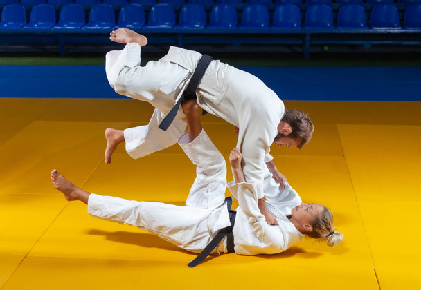 Bojová umění. Spořitelny. Sportovní muž a žena v bílém kimonu vlak judo hází a zachycuje ve sportovní hale - Fotografie, Obrázek