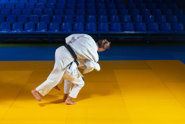 Kampfkunst. Schonen Portners. Sportler im weißen Kimono trainieren in der Sporthalle Judo-Werfen und -Fangen - Foto, Bild