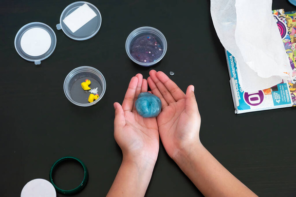 Uma vista de cima de uma jovem brincando com o Slime em uma mesa e tem-no comprimido em uma forma circular
.. - Foto, Imagem