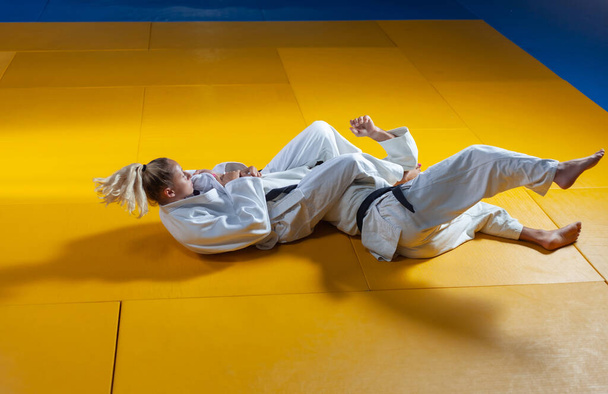 Боевые искусства. Подгоняю Портнеров. Спортивные мужчины и женщины в белом кимоно тренируются дзюдо бросает и захватывает в спортзале
 - Фото, изображение