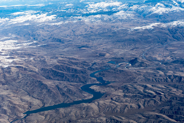Ilmakuva Idaho vuoret ja käärme joki taivaalta, kun sisällä lentokone. Näkymä ruskeat vuoret ja puut peitetty lumella - Valokuva, kuva