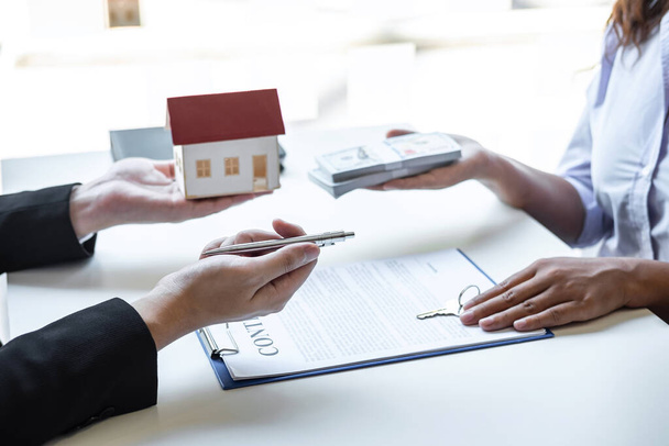 Immobilienmakler schickt Hausmodell an den Kunden nach Unterzeichnung des Vertrages Immobilien mit genehmigtem Hypothekenantragsformular, betreffend Hypothekendarlehensangebot und Hausversicherung. - Foto, Bild