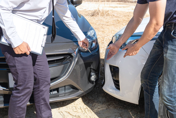 A biztosítási ügynök a balesetet követően megvizsgálja az autó sérülését a jelentési formanyomtatványon. - Fotó, kép