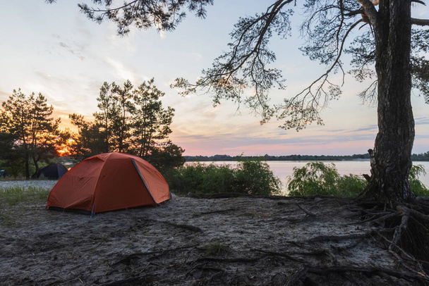 tents stand on the river bank at sunrise - Photo, Image