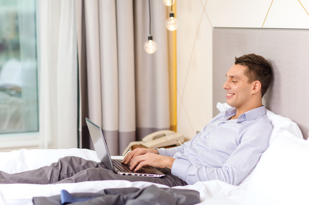 Happy businesswoman with laptop in hotel room - Photo, Image