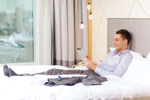 Happy businesswoman with tablet pc in hotel room - Foto, afbeelding