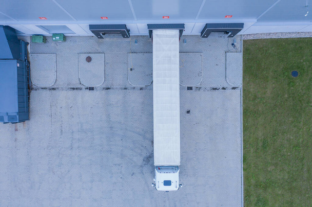 Vista aérea del almacén de mercancías. Centro logístico en zona industrial de ciudad desde arriba. Vista aérea de camiones cargando en el centro logístico - Foto, imagen