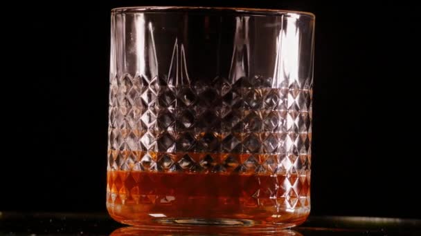 Whisky glass rotating before black background - Footage, Video