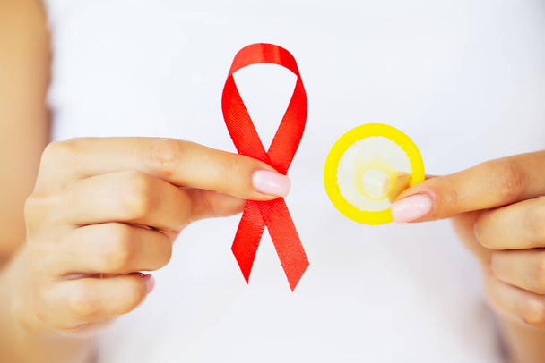 Frau hält Kondom und rote Schleife in der Hand und warnt vor AIDS - Foto, Bild