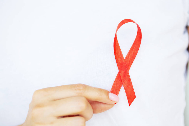 A woman holding a red ribbon emerges from a critical situation after overcoming AIDS - Photo, Image