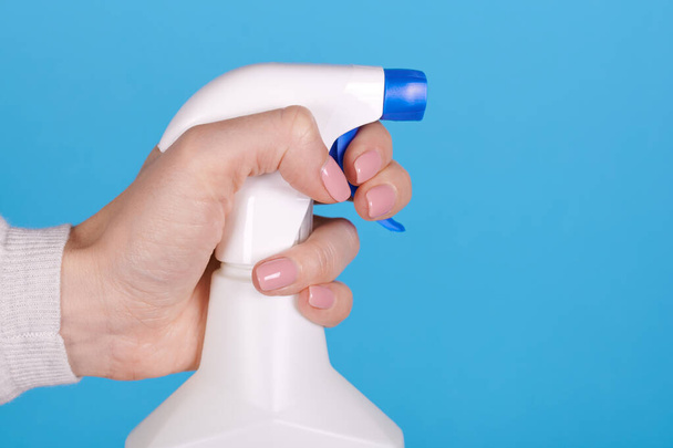 Cleaning spray bottle in hand on blue background. Close up photo. - Foto, immagini