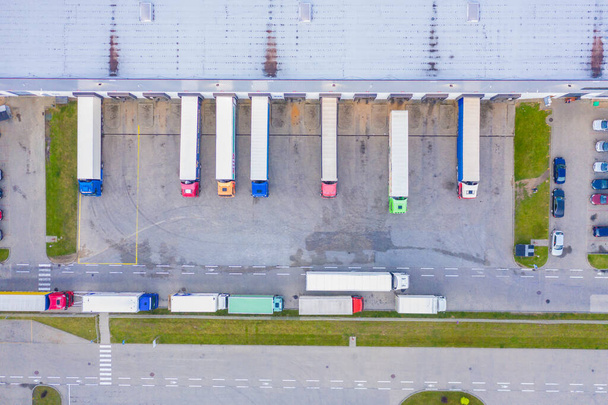 Vista aérea del almacén de mercancías. Centro logístico en zona industrial de ciudad desde arriba. Vista aérea de camiones cargando en el centro logístico. Vista desde el dron. - Foto, imagen