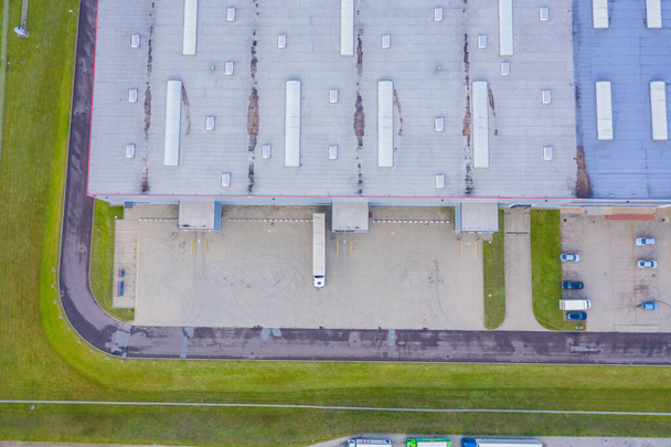 Vista aérea del almacén de mercancías. Centro logístico en zona industrial de ciudad desde arriba. Vista aérea de camiones cargando en el centro logístico - Foto, Imagen