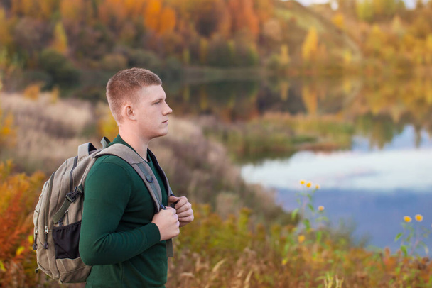 young tourist with  backpack near  autumn lake - Foto, afbeelding