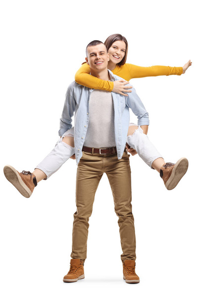 Guy carrying a happy cheerful young woman on his back isolated on white background - Foto, Bild