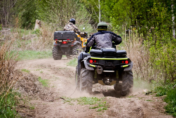 Selective focus. Two riders on ATVs ride on a dirt road. The concept of outdoor activities and extreme sports. - Photo, Image