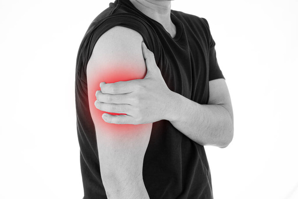 Black and white shot of man feeling exhausted and suffering from arm pain and injury on isolated white background with red spot. Health care and medical concept. - Photo, Image