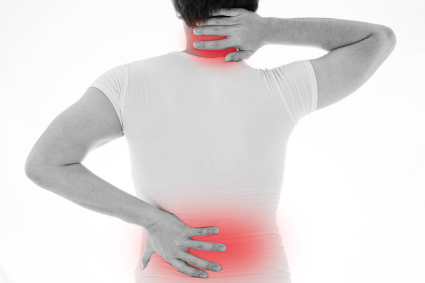 Black and white shot of man feeling exhausted and suffering from neck and back pain and injury on isolated white background with red spot. Health care and medical concept. - Photo, Image