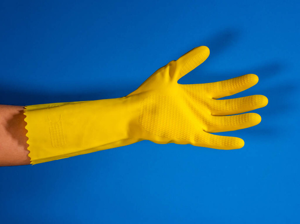 open girl hand with yellow cleaning gloves and blue background - Photo, Image