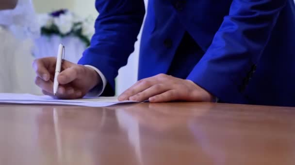 結婚式の間の新郎の兆候。スーツ姿の男の手が書類にサインを. - 映像、動画