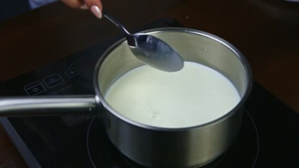 cámara lenta mano por cuchara agita la leche caliente con azúcar en una cacerola de metal
 - Imágenes, Vídeo
