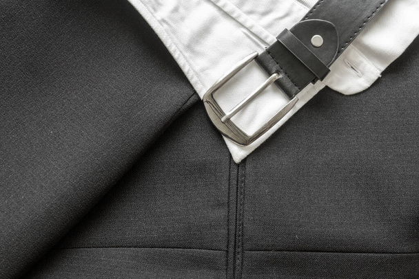 Close up of a business suit coat material and leather belt with white shirt collar - Fotoğraf, Görsel