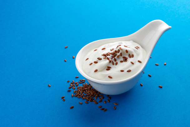 Fresh yogurt with flax seeds isolated on blue background - Photo, Image